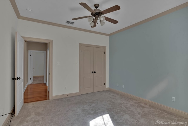 unfurnished bedroom featuring crown molding, a closet, light colored carpet, and ceiling fan