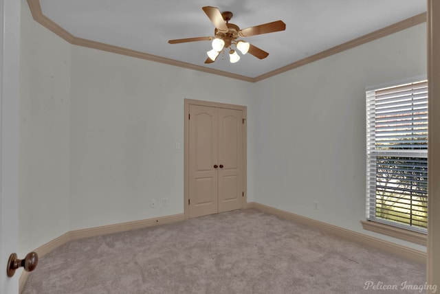 empty room with crown molding, light colored carpet, and ceiling fan