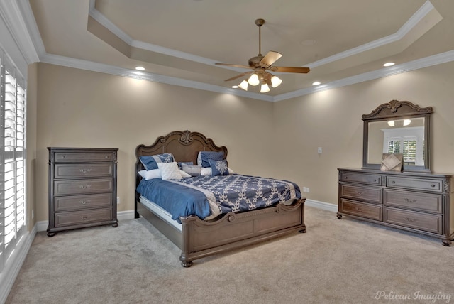 carpeted bedroom with crown molding, a tray ceiling, and ceiling fan