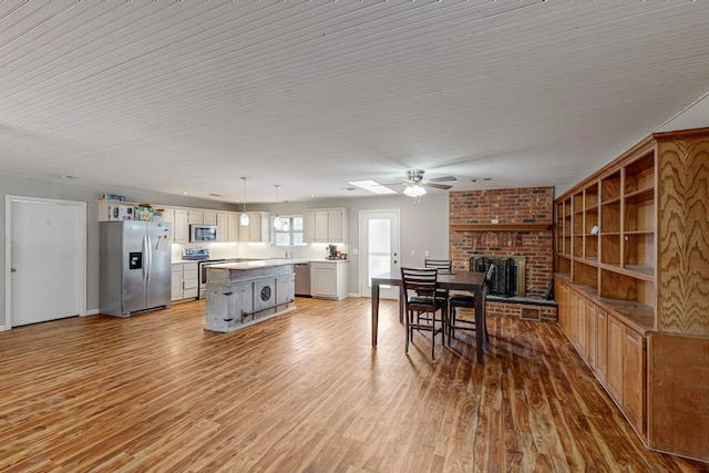 dining room featuring sink, a fireplace, light wood-type flooring, and ceiling fan