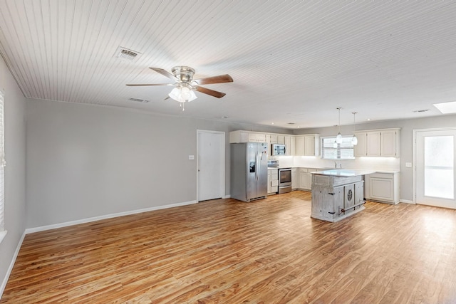 kitchen with hanging light fixtures, ceiling fan, appliances with stainless steel finishes, light hardwood / wood-style floors, and a center island