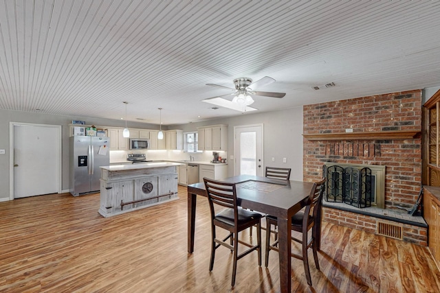 dining room featuring sink, ceiling fan, light hardwood / wood-style flooring, and a brick fireplace