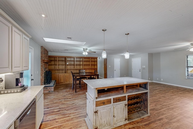 kitchen featuring pendant lighting, ceiling fan, a skylight, and light wood-type flooring