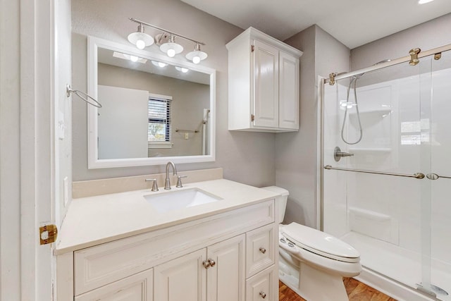 bathroom featuring a shower with door, vanity, hardwood / wood-style flooring, and toilet