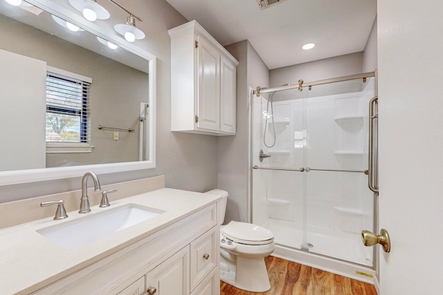 bathroom featuring a shower with door, vanity, hardwood / wood-style flooring, and toilet