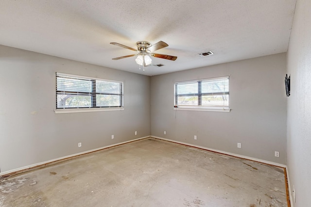 unfurnished room with ceiling fan, a healthy amount of sunlight, a textured ceiling, and concrete flooring