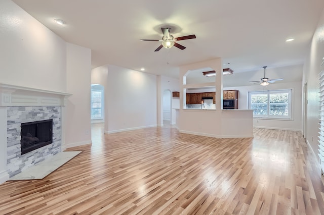 unfurnished living room with a fireplace, light wood-type flooring, and ceiling fan