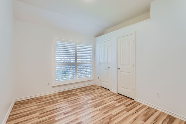 unfurnished bedroom featuring light hardwood / wood-style floors and lofted ceiling