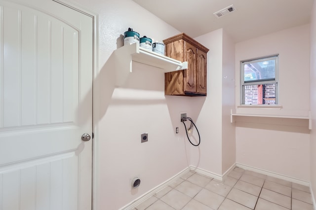 washroom with hookup for an electric dryer, washer hookup, light tile patterned floors, and cabinets