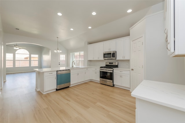 kitchen featuring lofted ceiling, white cabinets, kitchen peninsula, appliances with stainless steel finishes, and pendant lighting