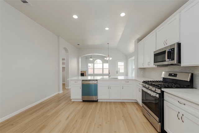 kitchen featuring kitchen peninsula, stainless steel appliances, vaulted ceiling, white cabinets, and light hardwood / wood-style flooring