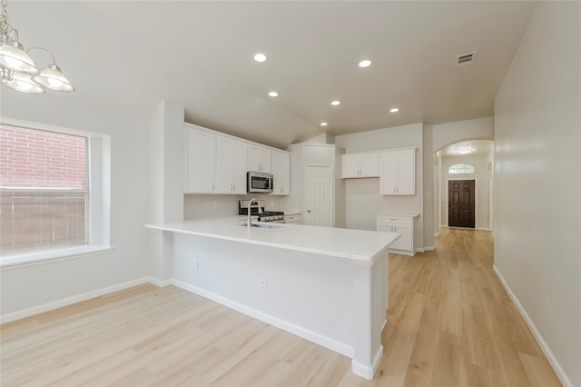 kitchen featuring light hardwood / wood-style floors, white cabinetry, stainless steel appliances, and pendant lighting