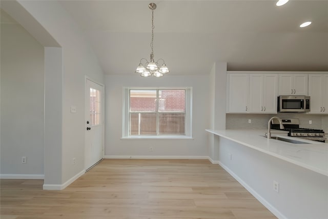 kitchen with decorative backsplash, appliances with stainless steel finishes, white cabinetry, light wood-type flooring, and sink