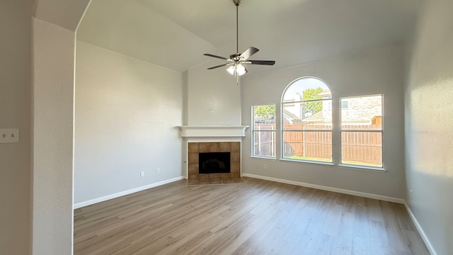 unfurnished living room with vaulted ceiling, light hardwood / wood-style flooring, a tiled fireplace, and ceiling fan