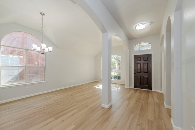 entrance foyer with light hardwood / wood-style floors, a notable chandelier, and lofted ceiling