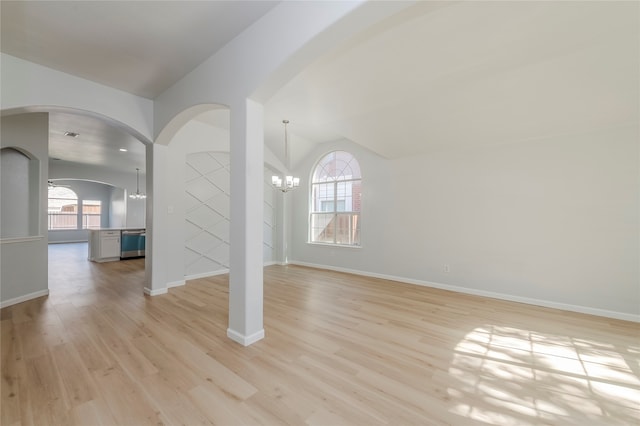 interior space with light hardwood / wood-style floors, an inviting chandelier, and vaulted ceiling