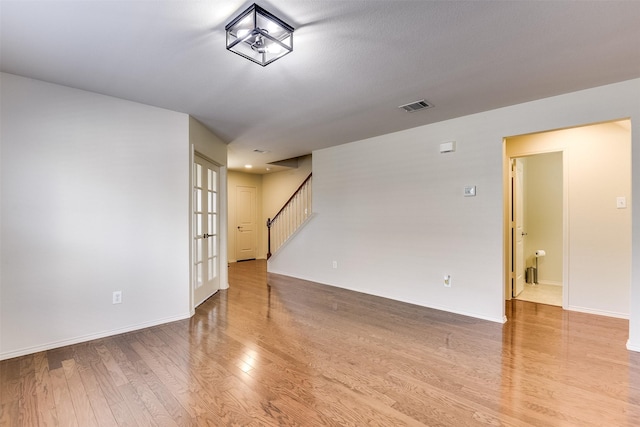 empty room with visible vents, baseboards, wood finished floors, and stairs