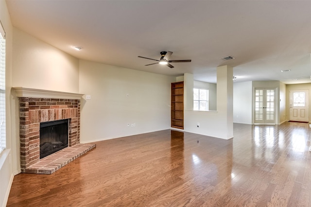 unfurnished living room with hardwood / wood-style flooring, a fireplace, ceiling fan, and french doors