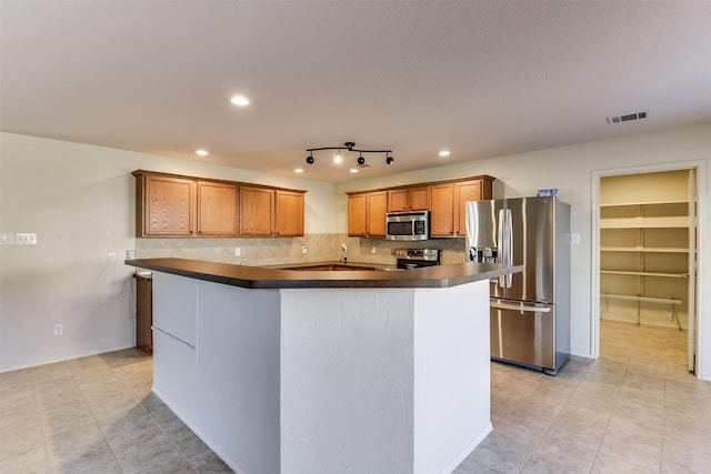 kitchen featuring backsplash, a kitchen island, light tile patterned flooring, and appliances with stainless steel finishes