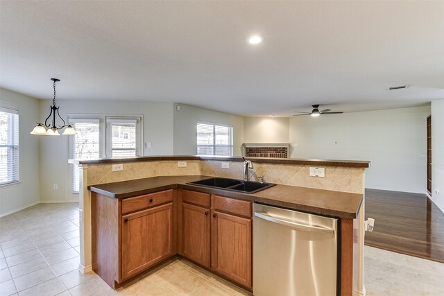 kitchen with dark countertops, open floor plan, dishwasher, and a sink