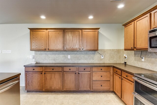 kitchen with dark countertops, stainless steel appliances, and brown cabinetry