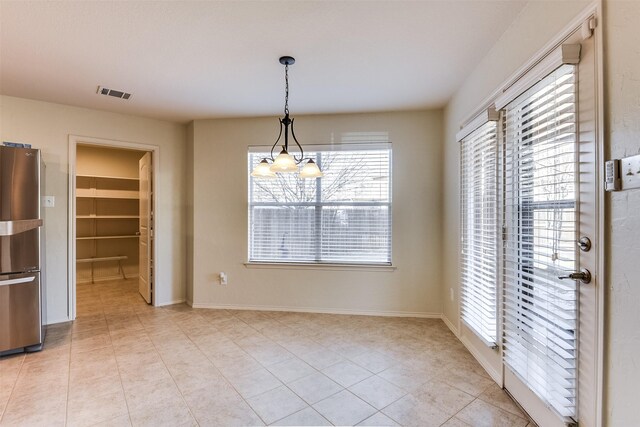 unfurnished dining area featuring light tile patterned flooring, visible vents, a chandelier, and baseboards