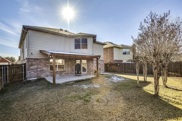 rear view of house with a patio area, brick siding, and a fenced backyard