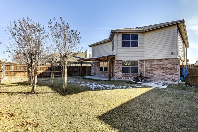 back of property with brick siding, a fenced backyard, a lawn, and a patio