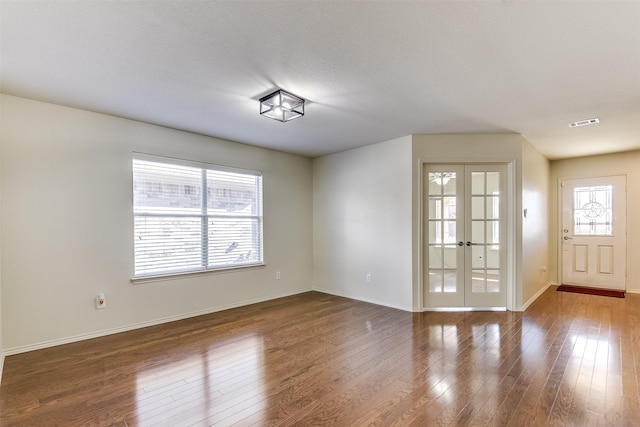 spare room with baseboards, french doors, wood-type flooring, and visible vents