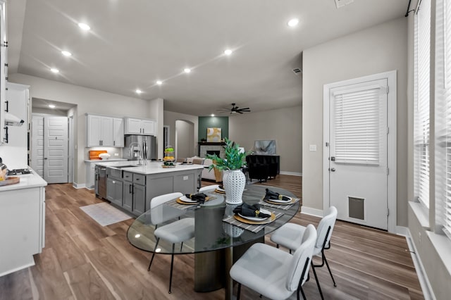 dining room featuring baseboards, recessed lighting, wood finished floors, arched walkways, and a ceiling fan