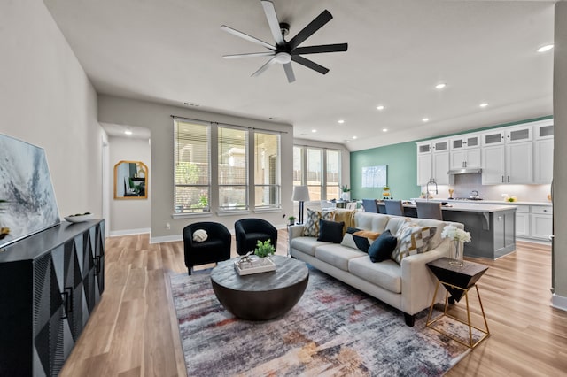 living room with ceiling fan and light hardwood / wood-style flooring