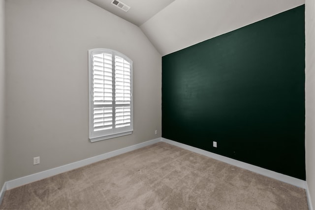 carpeted empty room featuring lofted ceiling