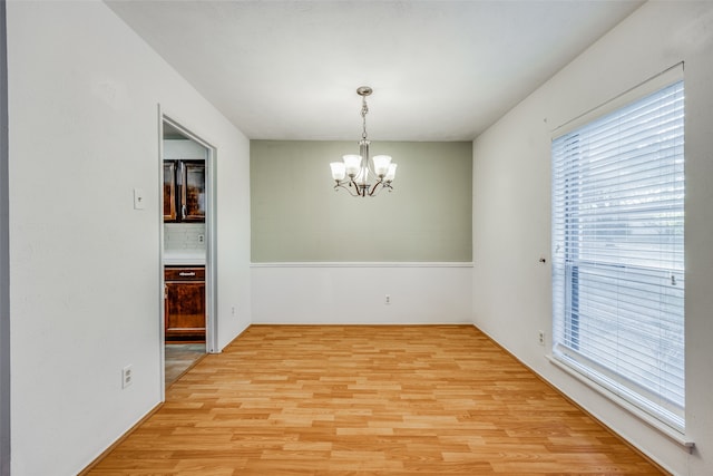 spare room featuring light hardwood / wood-style floors and an inviting chandelier