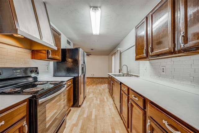 kitchen with decorative backsplash, light hardwood / wood-style flooring, stainless steel appliances, sink, and ventilation hood