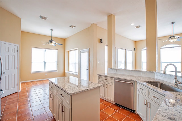 kitchen featuring stainless steel dishwasher, sink, light stone countertops, and light tile patterned flooring