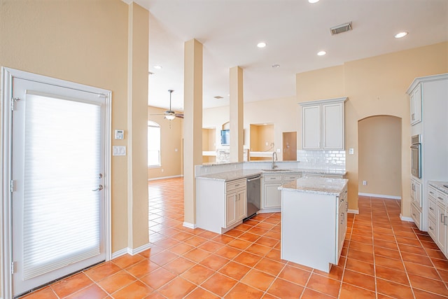 kitchen with kitchen peninsula, white cabinets, light tile patterned floors, appliances with stainless steel finishes, and sink