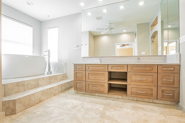 bathroom with vanity, a relaxing tiled tub, and ceiling fan