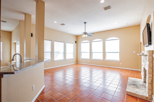 unfurnished living room with ceiling fan, light tile patterned floors, and a fireplace