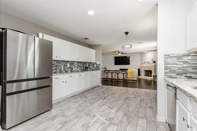 kitchen featuring light hardwood / wood-style floors, white cabinets, stainless steel appliances, and a fireplace