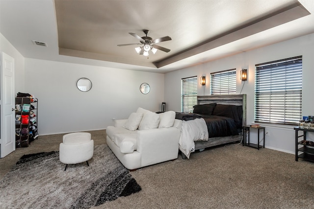 carpeted bedroom with a tray ceiling and ceiling fan