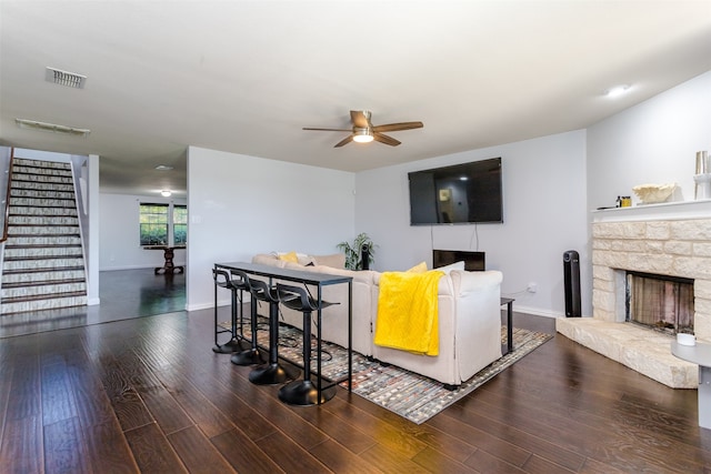 living room featuring ceiling fan, a fireplace, and dark hardwood / wood-style flooring