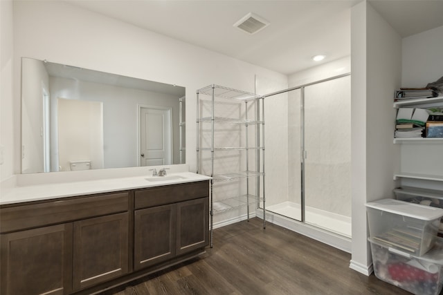 bathroom featuring wood-type flooring, vanity, toilet, and a shower with door