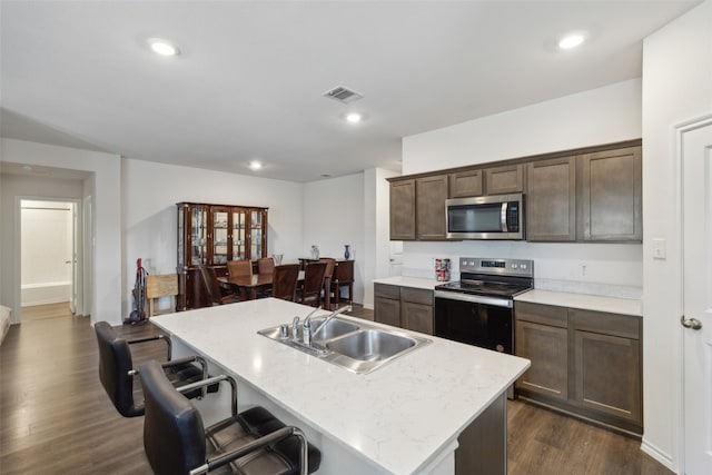 kitchen with an island with sink, stainless steel appliances, dark hardwood / wood-style floors, and sink