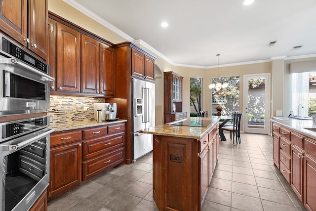 kitchen featuring stainless steel appliances, a center island, backsplash, light stone countertops, and crown molding