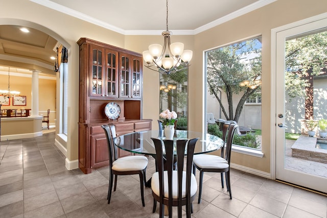 dining space featuring decorative columns, a chandelier, arched walkways, and crown molding