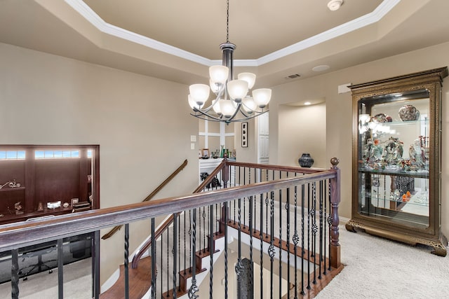 corridor with a raised ceiling, an upstairs landing, and crown molding