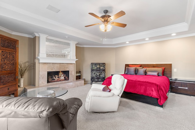 carpeted bedroom with ceiling fan, recessed lighting, a premium fireplace, a tray ceiling, and crown molding