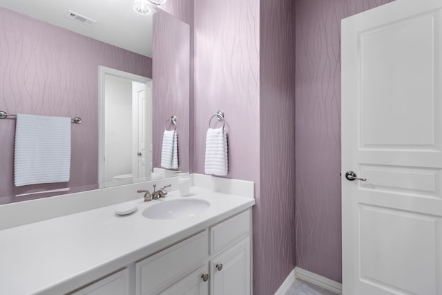 bathroom with toilet, visible vents, and vanity