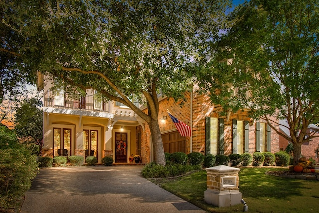 view of front of home featuring a balcony, covered porch, and a front lawn