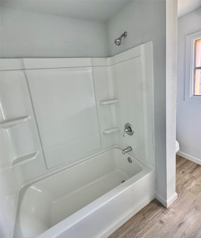 bathroom with toilet, hardwood / wood-style floors, and washtub / shower combination